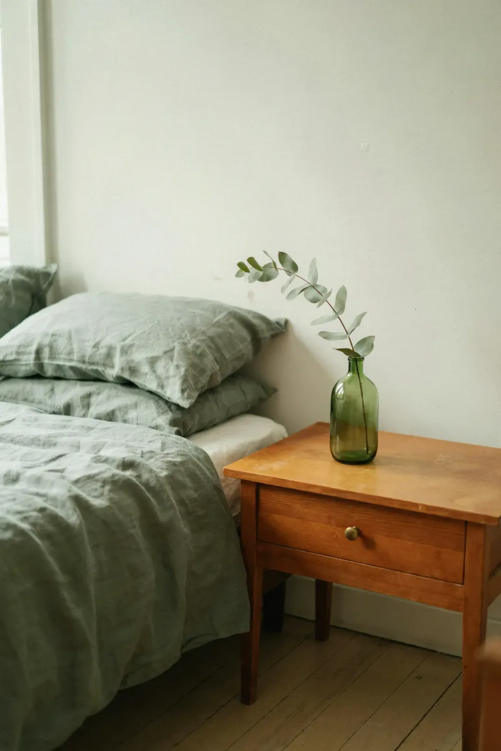 Warm sage green bedroom: finish the Nightstand With a Green Glass Vase